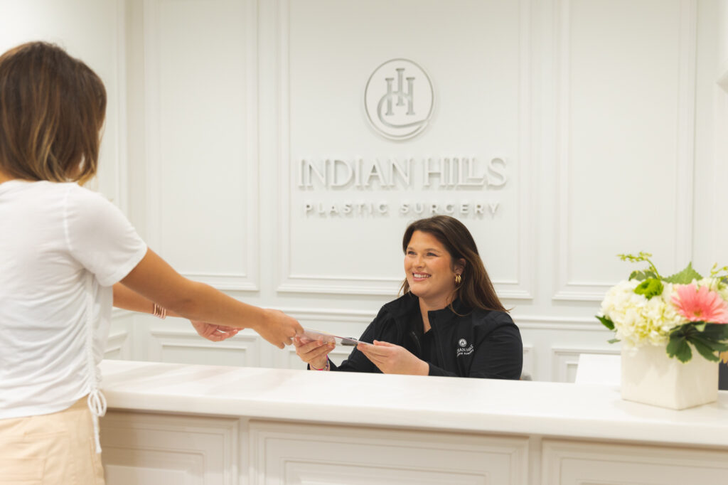 Patient Handing a Clipboard to a Front Desk Attendant at Indian Hills Plastic Surgery
